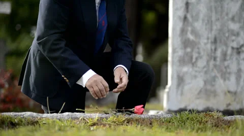 Elderly man kneeling down to lay flower on grave Stock Footage 23109407