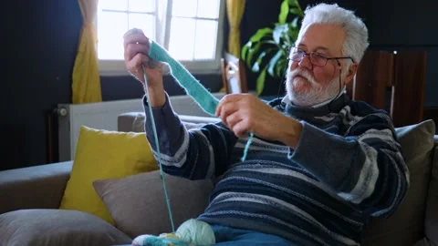 Elderly man knitting from wool yarn using knitting needles. Video stock 165114429