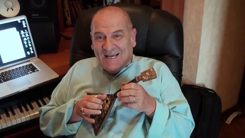 Elderly man of large physique jokingly plays on a little toy balalaika Stock Footage 75858225