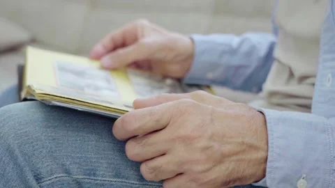 An elderly man is leafing through a photo album. Vidéo 160978322