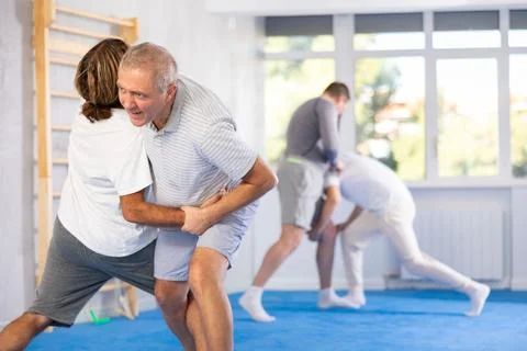Elderly man learning judo technique with trainer in sport gym Stock Photos