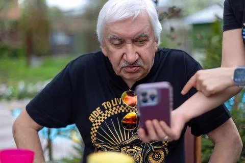 Elderly man learning smartphone with help. Senior man being taught how to use a Stock Photos