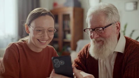 Elderly Man Learning to Use Mobile App on Smartphone with Help from Daughter Stock Footage 305723991