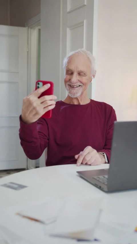 An elderly man learns to take a selfie. He is serious at first, and then relaxes Stock Footage 173566979