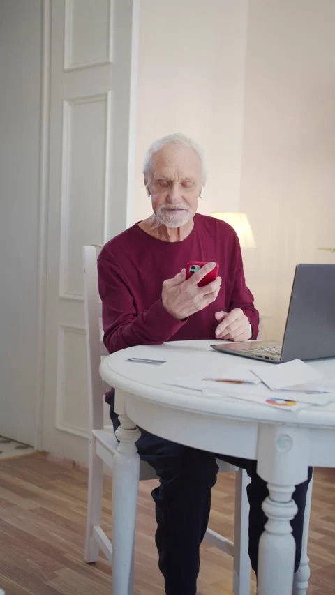 An elderly man learns to use video calling on his phone. He is talking to a Stock Footage 173567187