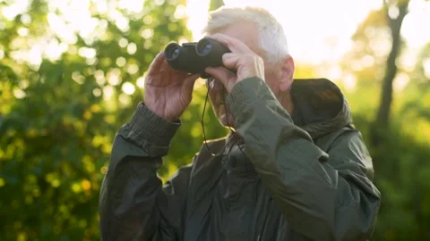 Elderly man looking through binoculars outdoors close up. Video stock 138503062