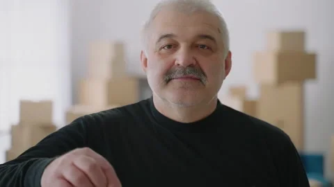 An elderly man looks at the camera smiling and showing the keys to the new Stock Footage 149323358