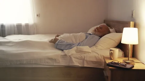 Elderly man lying in bed, missing his family, feeling isolated in old age Stock Footage 310009072