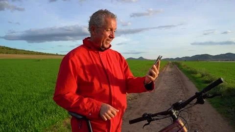 Elderly man makes a video call and greets cameraman while doing sports with.. Stock Footage 225712262