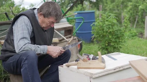 An elderly man makes a wooden box at the cottage in the summer Stock Footage 155793473