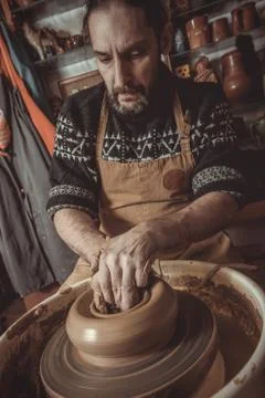 Elderly man making pot using pottery wheel in studio Stock Photos