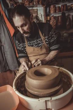 Elderly man making pot using pottery wheel in studio Stock Photos