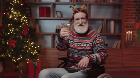 Elderly Man Making Video Call while Sitting in Wheelchair, Raising the Glass and Stock Footage 254771612