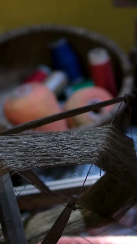 An elderly man meticulously weaves a delicate fabric using a old antique Stock Footage 318385083