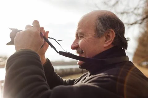An elderly man with a mirrorless camera chooses a frame on nature Stock Photos
