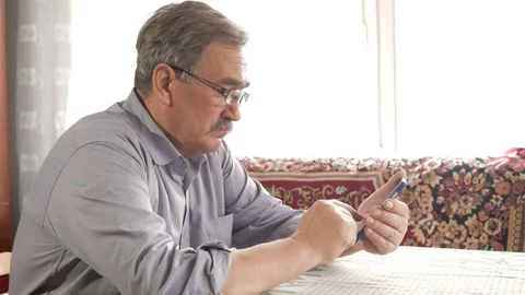 An elderly man with a mustache in glasses dials a text message on his mobile Stock Footage 74932015