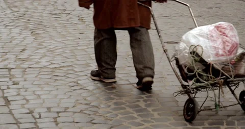An elderly man in old clothes pulls a cart with his belongings Stock Footage 240027009