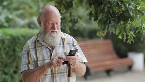 Elderly man at the park typing on mobile phone Video stock 80436968