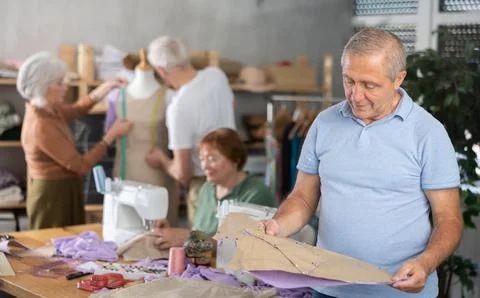 Elderly man with pattern at sewing master class Foto stock