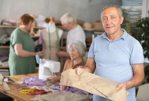 Elderly man with pattern at sewing master class Foto stock