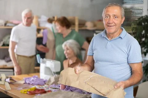 Elderly man with pattern at sewing master class Stockfoto's