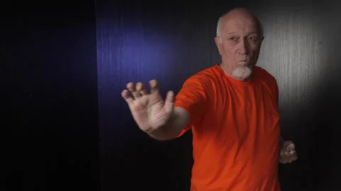 An elderly man performs blocks and punches while moving Stock Footage 312096715