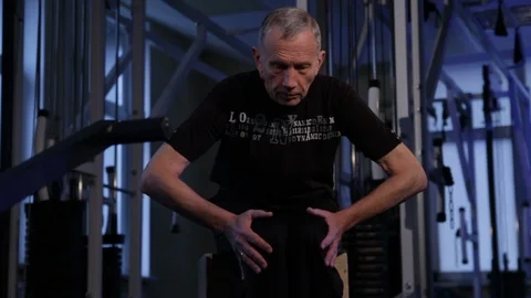 An elderly man performs isometric exercise, kneeling to the sides.front view Stock Footage 115934896