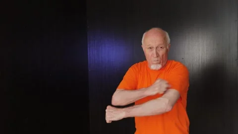 An elderly man performs punches and blocks with his hands Stock Footage 312096884