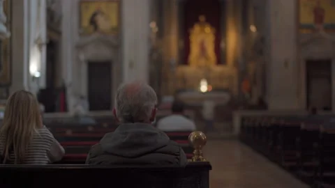 Elderly man prays while sitting on bench inside church, rear view. Catholic Stock-Footage 180156265