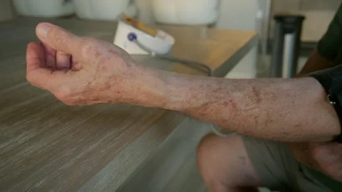 Elderly man puts on the cuff to take his blood pressure reading in the afternoon Видео 329004531