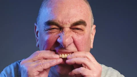 Elderly man puts false teeth into his mouth. Periodontal disease and missing Stock Footage 236024210