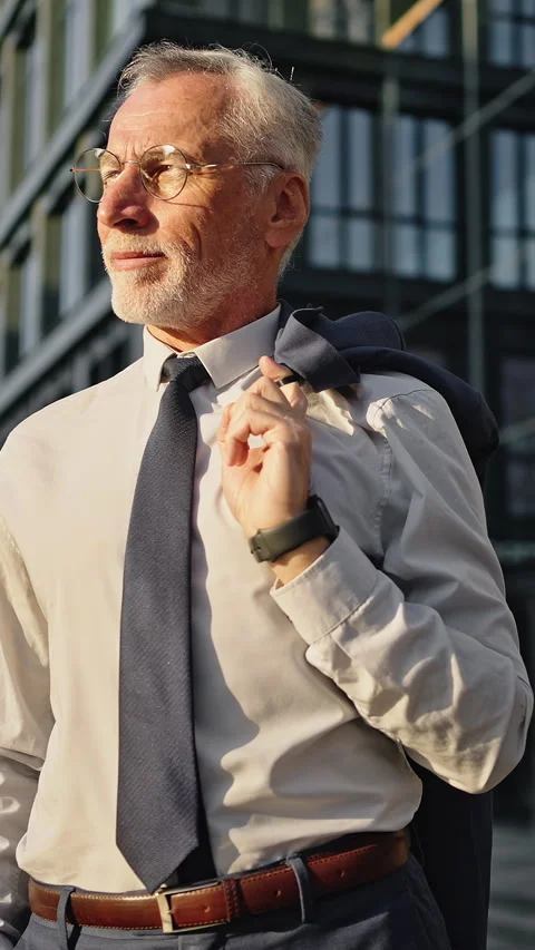 Elderly man puts jacket on shoulder standing on city street Stock Footage 329785339