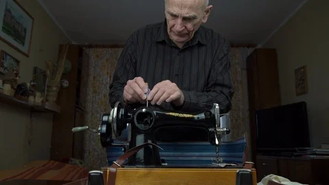Elderly man puts thread spool on pin and adjusts hand wheel Video stock 128572776