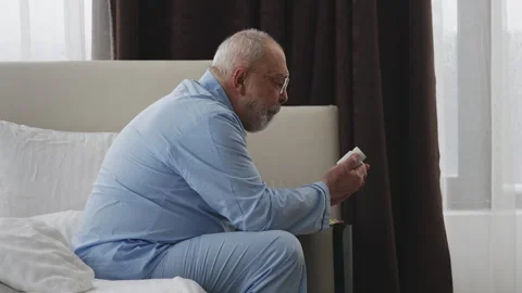 Elderly man putting on glasses and reading label on prescription pill bottle Stock Footage 346485437