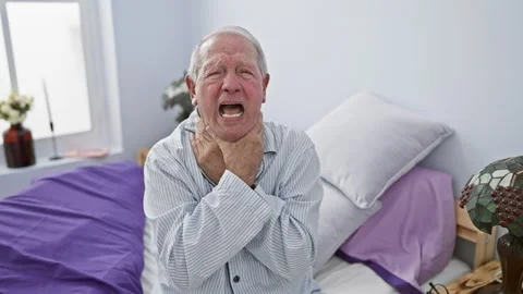 Elderly man in pyjamas wearing pained expression as he suffocates, strangle.. Stock Footage 268572937