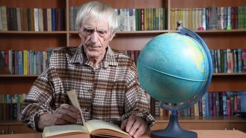 Elderly man reading book in library near globe 動画素材 167061931