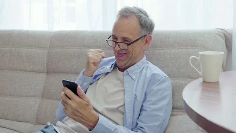 Elderly man rejoices looking into smartphone Stock Footage 160983604