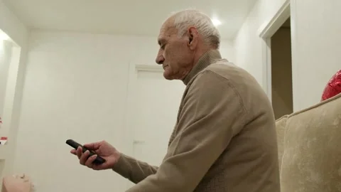 Elderly man resting on a comfortable sofa in his living room, attentively 스톡 동영상 342069400