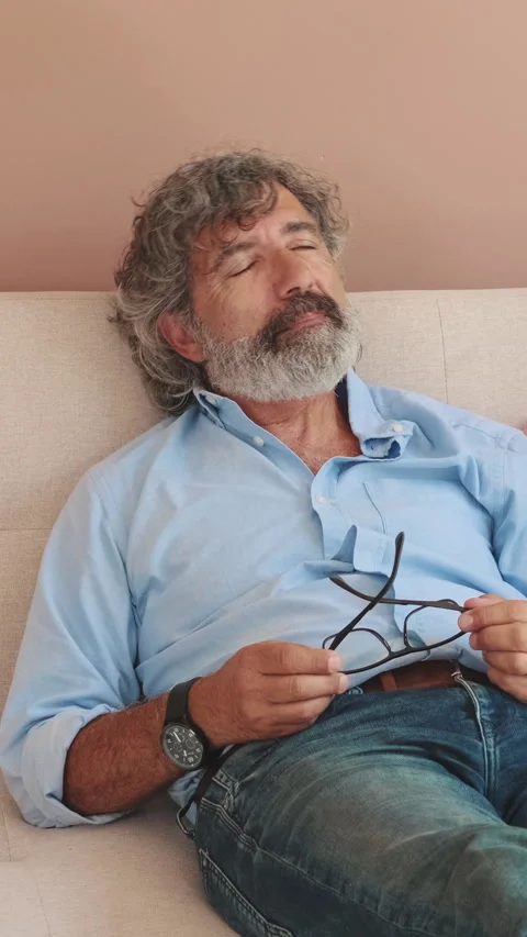 An elderly man is resting lying on the sofa in cozy living-room Stock Footage 255963071