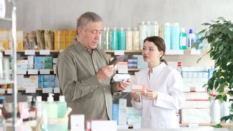 Elderly man scans QR code on box ointment label. Female pharmacist offers Stock Footage 319487024