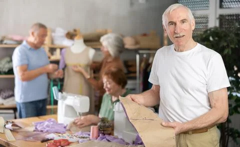 Elderly man showing paper pattern in training sewing workshop Stock Photos