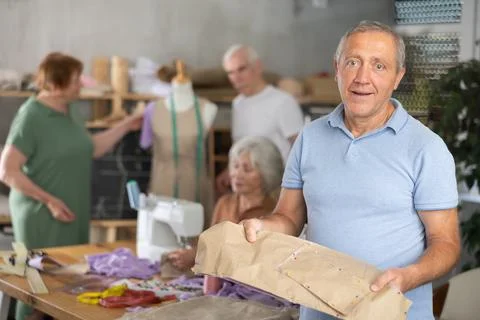 Elderly man showing paper pattern in training sewing workshop Foto stock