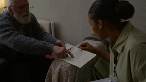 Elderly Man Showing Utility Bills to Black Female Social Worker at Home Stock Footage 329682311