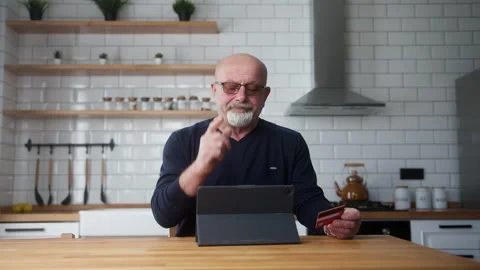 Elderly man sit in kitchen enter credit card number on tablet and due insuf.. Stock Footage 269929247