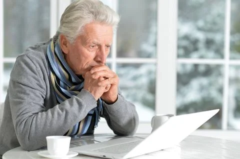 Elderly man sits on the background of the window in winter Stock Photos