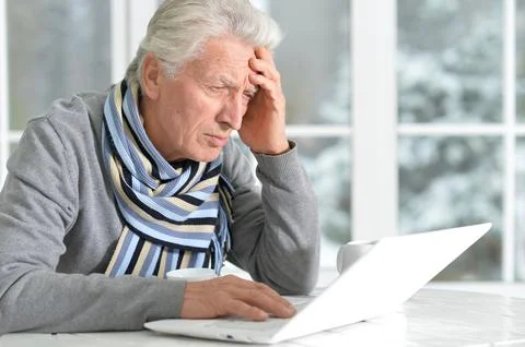 Elderly man sits on the background of the window in winter Stock Photos