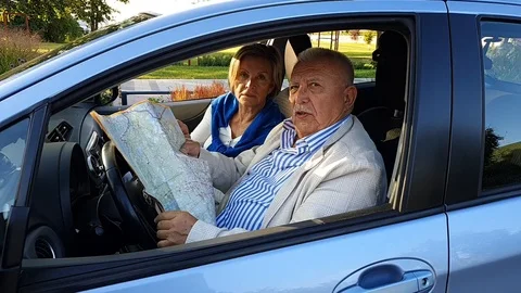 Elderly man sitting behind steering wheel shows travel map Stock Footage 127182280