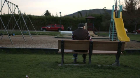 Elderly Man sitting on bench in playground Stock Footage 37345341