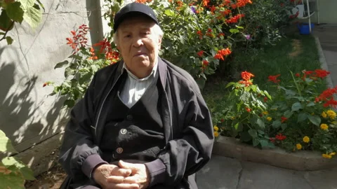 An elderly man is sitting in his yard. Stock Footage 162958355