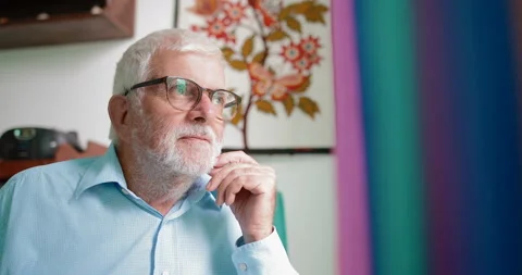 An elderly man sitting by the window and looking out the window Stock Footage 105402428